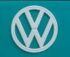 Close-up of a vintage Volkswagen emblem on a teal van, showcasing classic design and color.